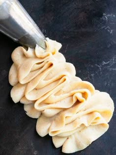 some kind of food that is being made on a black surface with a metal spoon