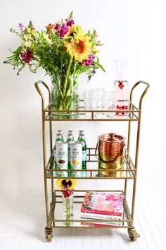 a gold bar cart with drinks and flowers