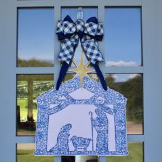 a blue and white christmas door hanger with a nativity scene in the center