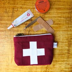 the contents of a first aid kit laid out on a wooden table, including an orange and white cross