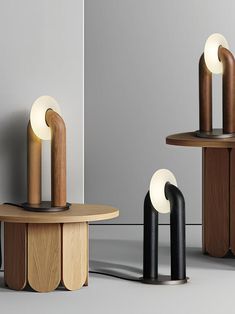 three wooden tables with different shapes and sizes on each table, one has a light that is shaped like an ovoid