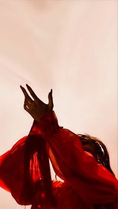 a woman in a red dress with her hands up