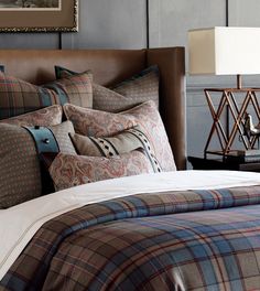 a bed with plaid comforter and pillows on it