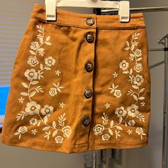 Camel Brown With White Flower Embroidery On The Side. Chunky Buttons Lining The Front. Material Is Like A Corduroy/Denim. Never Worn. Size Small, Runs About A Size 1/2. Spring Embroidered Beige Skirt, Casual Embroidered Fall Skirt, Fairy Academia, White Flower Embroidery, Skirt Embroidery, Embroidery Skirt, Brown Flower, Faux Leather Mini Skirt, Cloth Flowers