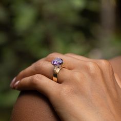 a woman's hand with a ring on it and a purple stone in the middle