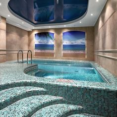 an indoor swimming pool with steps leading up to it and the ocean in the background