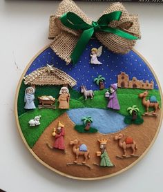 a christmas ornament with nativity scenes on it and a green bow hanging from the wall