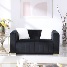 a black couch with two white pillows on top of it in front of a coffee table