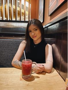 a woman sitting at a table with a drink