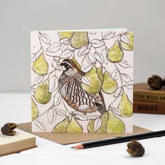 a card with an image of a bird in a pear tree on it, surrounded by books and pencils