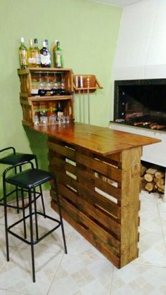 a bar made out of wooden pallets in front of a fire place with two stools