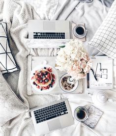 an aerial view of a bed with laptops, flowers and coffee on the side