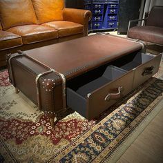 a brown leather trunk sitting on top of a rug next to a couch and chair