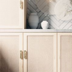 a white vase sitting on top of a wooden cabinet