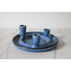 three blue candlesticks sitting on top of a ceramic tray with marbled surface