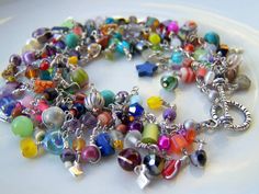 a multicolored beaded bracelet with charms on a white plate in front of a window