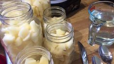 several jars filled with food sitting on top of a wooden table next to utensils