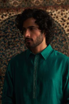 This emerald green pathani kurta set is a stunning choice for festive occasions like mehendi. The subtle embroidery on the placket adds a touch of elegance without being over the top. Paired with a coordinating salwar in a color-on-color design, it strikes the perfect balance between traditional and stylish. This set is sure to become a go-to piece in your wardrobe for celebrating special moments! Festive Cotton Silk Kurta With Naqshi Detail, Designer Green Salwar Kameez With Naqshi, Festive Green Naqshi Salwar Kameez, Green Long Sleeve Lawn Suit With Zari Work, Elegant Green Kurta With Mirror Work, Green Kurta With Dabka Work In Cotton Silk, Green Lawn Suit With Mirror Work, Green Chanderi Lawn Suit With Long Sleeves, Green Cotton Silk Kurta With Dabka Work