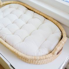 a wicker baby bed sitting on top of a white table next to a window