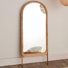 a mirror sitting on top of a wooden floor next to a wall