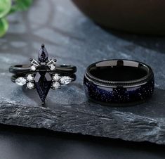 two rings with diamonds on them sitting next to each other in front of a rock