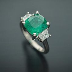 This Elegant Platinum three stone ring has a Natural Cushion Cut Colombian Emerald from the Top Muzo Mine with a GIA Certificate. The side stones are Natural Brilliant Cut Trapezoid Pair of Matching Diamonds. GIA#5202111099 3.34 Carat Cushion Modified 9.64x8.93x5.64 with moderate F2 clarity enchancement. 2 Matching Trapezoid Brilliant Cut Diamonds weigh 0.71 carats total weight and are graded G in color and SI1 to SI2 in clarity. Platinum weight is 5.14 DWT. Ring can be sized. Three Stone Diamond Gemstones For Anniversary, Luxury Three Stone Gemstones For Anniversary, Luxury Three Stone Emerald Ring For Formal Events, Luxury Three Stone Emerald Ring For Formal Occasions, Luxury Emerald Three Stone Ring For Formal Occasions, Luxury Three-stone Emerald Ring, Formal Three Stone Emerald Ring In Fine Jewelry Style, Three Stone Diamond Gemstones For Wedding, Green Three Stone Fine Jewelry