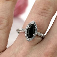 a woman's hand with a black and white diamond ring on top of it