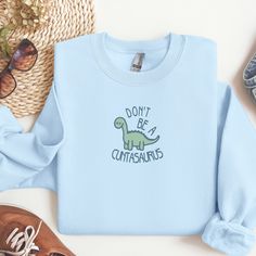 Get your wardrobe and attitude in check with our Embroidered "Get Your Shit Together" Crewneck. Crafted from a comfortable 50/50 cotton-polyester blend, this crewneck is perfect for adding a touch of sass to your everyday style. The standout design features a charming daisy accentuated with the bold and empowering phrase "Get Your Shit Together". Available in a range of sizes from S to 2XL, and in colors including Dark Chocolate, Indigo Blue, Light Blue, Light Pink, Military Green, Navy, Sand, Sport Grey, and White. Please refer to the size chart included in the images for the perfect fit. Please note that colors may vary slightly due to monitor settings. Casual Cotton Sweatshirt With Dinosaur Print, Casual Dinosaur Print Crew Neck Sweatshirt, Cotton Tops With Dinosaur Print For Fall, Cotton Top With Dinosaur Print For Fall, Casual Dinosaur Print Tops For Fall, Casual Blue Top With Dinosaur Print, Sassy Sweatshirts, Funny Dinosaur, Dinosaur Funny