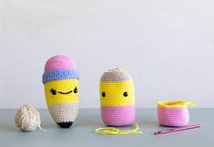 three crocheted items sitting on top of a table next to balls of yarn