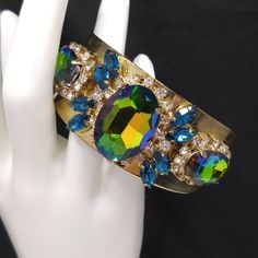 *Description: This is a gorgeous watermelon rhinestone crystal bracelet on a golden brass cuff which glitters and sparkles in the light. The vintage rhinestones are secured on a golden brass cuff and the reflective cuff adds additional sparkle to the bracelet. There is one large watermelon rhinestone in the center, surrounded by clear rhinestones and sapphire blue marquise cut rhinestones. On each side of the center stone are two more watermelon rhinestones, a little smaller in size, one on each Crystal Bangle Cuff Bracelet For Party, Glamorous Jeweled Bracelets For Party, Glamorous Crystal Cuff Bracelet For Party, Glamorous Bangle Crystal Bracelet For Parties, Glamorous Rhinestone Cuff Bangle Bracelet, Glamorous Sparkling Bangle Crystal Bracelet, Glamorous Sparkling Stones Bracelets For Party, Glamorous Sparkling Crystal Bangle Bracelet, Glamorous Sparkling Stones Bracelet For Party