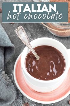 a white bowl filled with hot chocolate next to a spoon