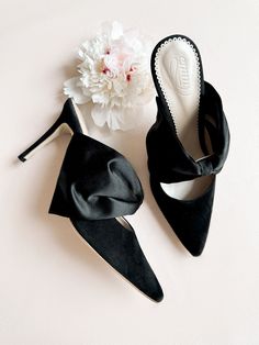 Our new style, Georgia Mid Heel in jet black suede with a beautiful bow, sits on a slim 85mm heel. The flattering mule silhouette is finished with a lustrous black silk satin bow secured onto the metallic leather strap for a show stopping finish! Handmade using the most beautiful Italian suede that is super soft and kind to your feet. This mid-height style is wonderfully comfortable and perfect for your special occasion and beyond... Bridal Shoes Green, Mule Silhouette, Low Heel Flats, Blue Bridal Shoes, Ivory Bridal Shoes, Pink Wedding Shoes, London Logo, Ivory Wedding Shoes, London Shoes