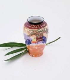 a vase sitting on top of a white table next to a green leafy plant