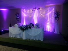 an image of a banquet room setting with purple lighting and flowers on the table top