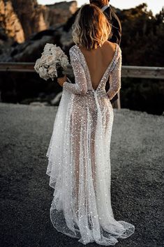 the back of a bride's dress with sequins on it and her bouquet