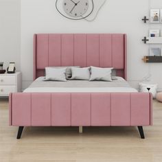 a pink bed sitting in a bedroom next to a white dresser and clock on the wall