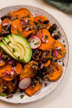 a white plate topped with sweet potatoes and avocado