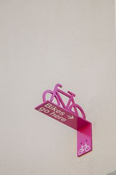 a pink bicycle sign mounted to the side of a building