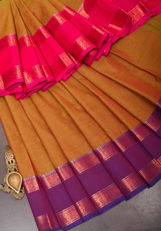 It is said that when weaving practices first began at Kanchipuram centuries back, the weavers used cotton as their primary base. Even though the Kanjivaram silk has taken predominance, the cotton sarees of this town have stood the test of time and have gained popularity. This all-natural Kanchi cotton saree in an eye-pleasing color contrast carries the sophisticated charm that is attributed to sarees made in the looms of Kanjivaram. The wide border decorated with traditional motifs in zari enhan Transitional Cotton Silk Traditional Wear For Rituals, Cotton Silk Traditional Wear For Rituals, Traditional Cotton Silk Wear With Zari Weaving For Rituals, Cotton Silk Traditional Wear For Rituals And Festivals, Raw Silk Traditional Wear With Zari Weaving For Rituals, Traditional Raw Silk Wear With Zari Weaving For Rituals, Traditional Slub Silk Wear With Border, Raw Silk Traditional Wear With Cutdana For Rituals, Gold Cotton Silk Saree With Weaving Work