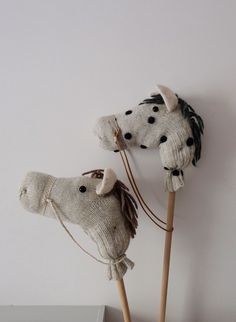 two knit horse heads are on sticks in front of a white wall with black dots