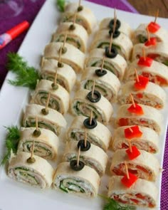 a white plate topped with rolls covered in meat and veggies on skewers