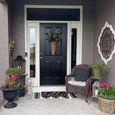 the front door is decorated with potted plants and two wicker chairs on the porch