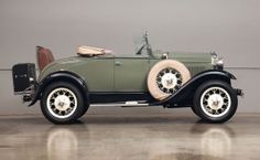 an old model green car parked in a garage