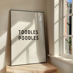 a poster that says toodles poodles on the wall next to a window