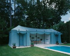 a pool cabana in the middle of a backyard with a swimming pool next to it