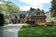 a large house with lots of trees and flowers in the front yard