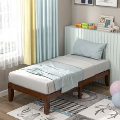 a child's bed with blue sheets and pillows in a small room next to a window