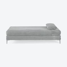 a gray chaise lounger with pillows on the top and bottom, sitting against a white background