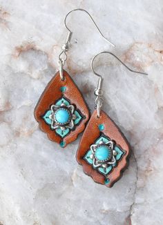 These petite earrings have vintage turquoise and sterling silver pieces mounted on a leather earring.  The turquoise and sterling pieces were originally clip on earrings I found at an estate sale - I mounted them to the leather, then accented them with stamping, dye and paint.    1 7/8" long including the ear wire, 3/4" wide. Hand Tooled Leather Drop Earrings, Artisan Leather Nickel-free Earrings, Concho Dangle Earrings For Gift, Artisan Turquoise Concho Earrings, Bohemian Turquoise Leather Earrings, Elegant Concho Earrings For Gift, Turquoise Concho Dangle Jewelry, Artisan Leather Teardrop Earrings, Handmade Turquoise Leather Earrings