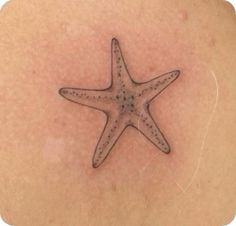 a starfish tattoo on the back of a woman's shoulder